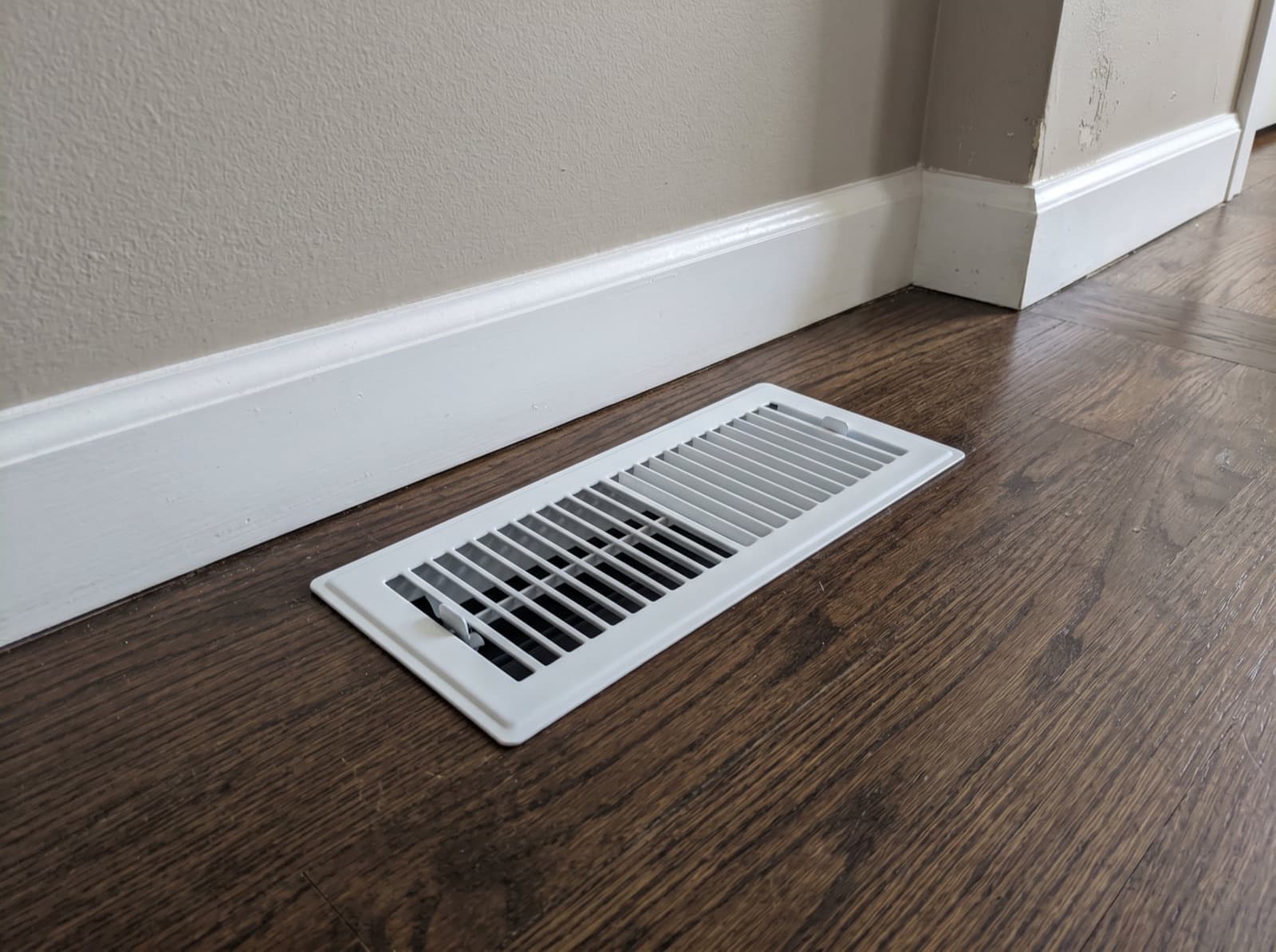 New floor duct register installed on hardwood.