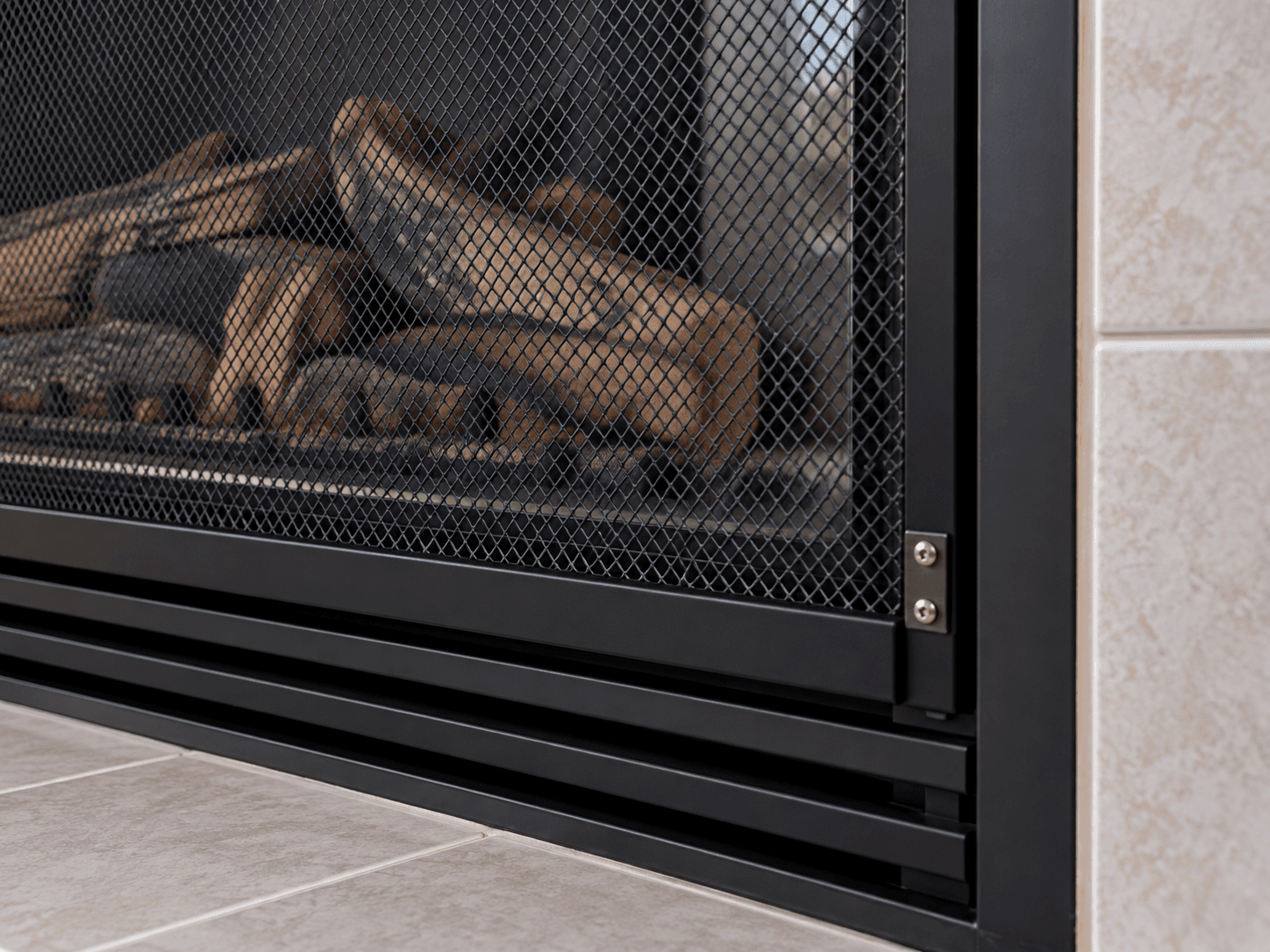 A fine safety mesh barrier secured in front of closed gas-fireplace glass.