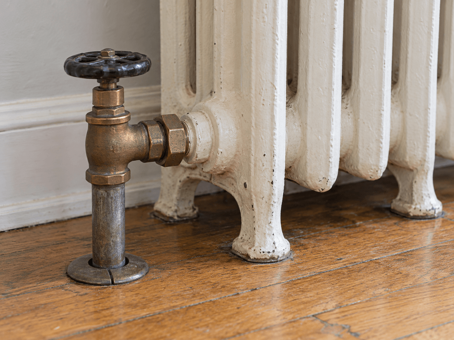 The lower water connection and manual valve on a radiator, with the pipe and fittings intact.