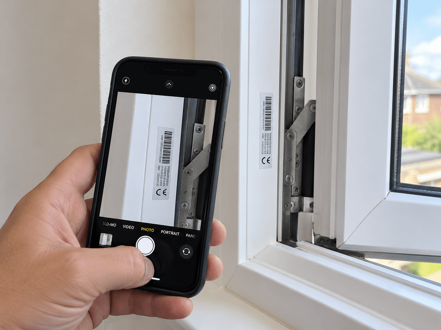 A homeowner photographs the accessible identification label on an open window frame.