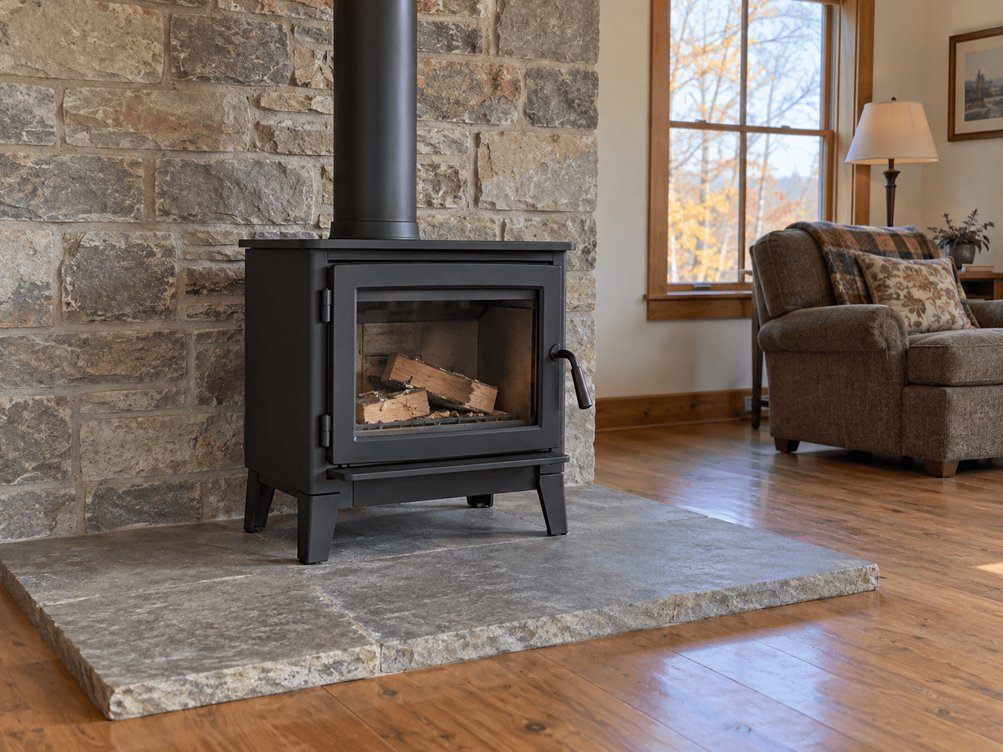 An unlit wood stove with its door closed on a stone hearth, with a straight stovepipe and clear surrounding space.