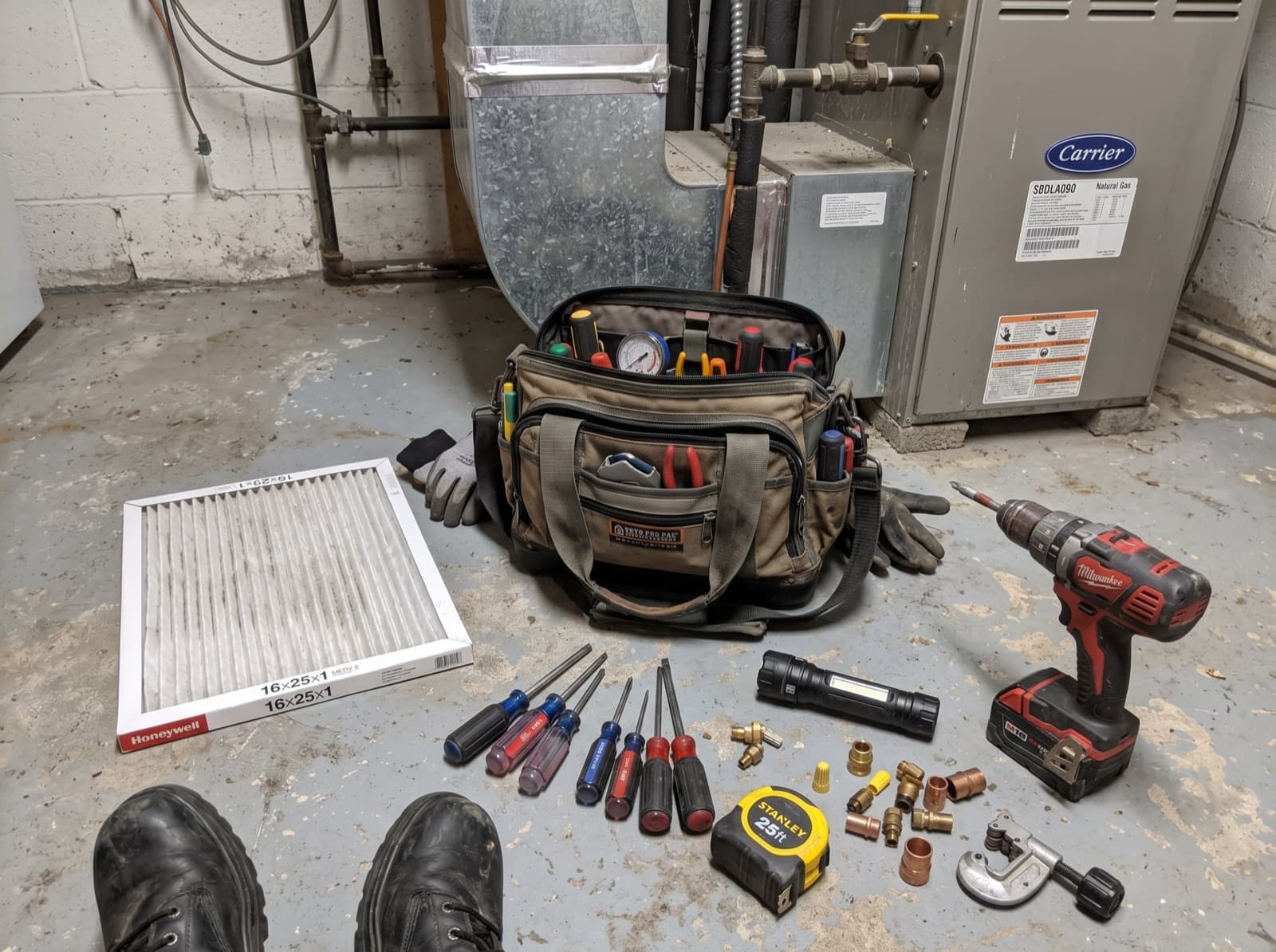 Maintenance tools and filter laid out on a basement floor.